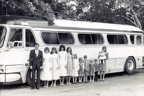 The John Marshall Family standing in a row in front of their tour bus, 1984, black-and-white photo